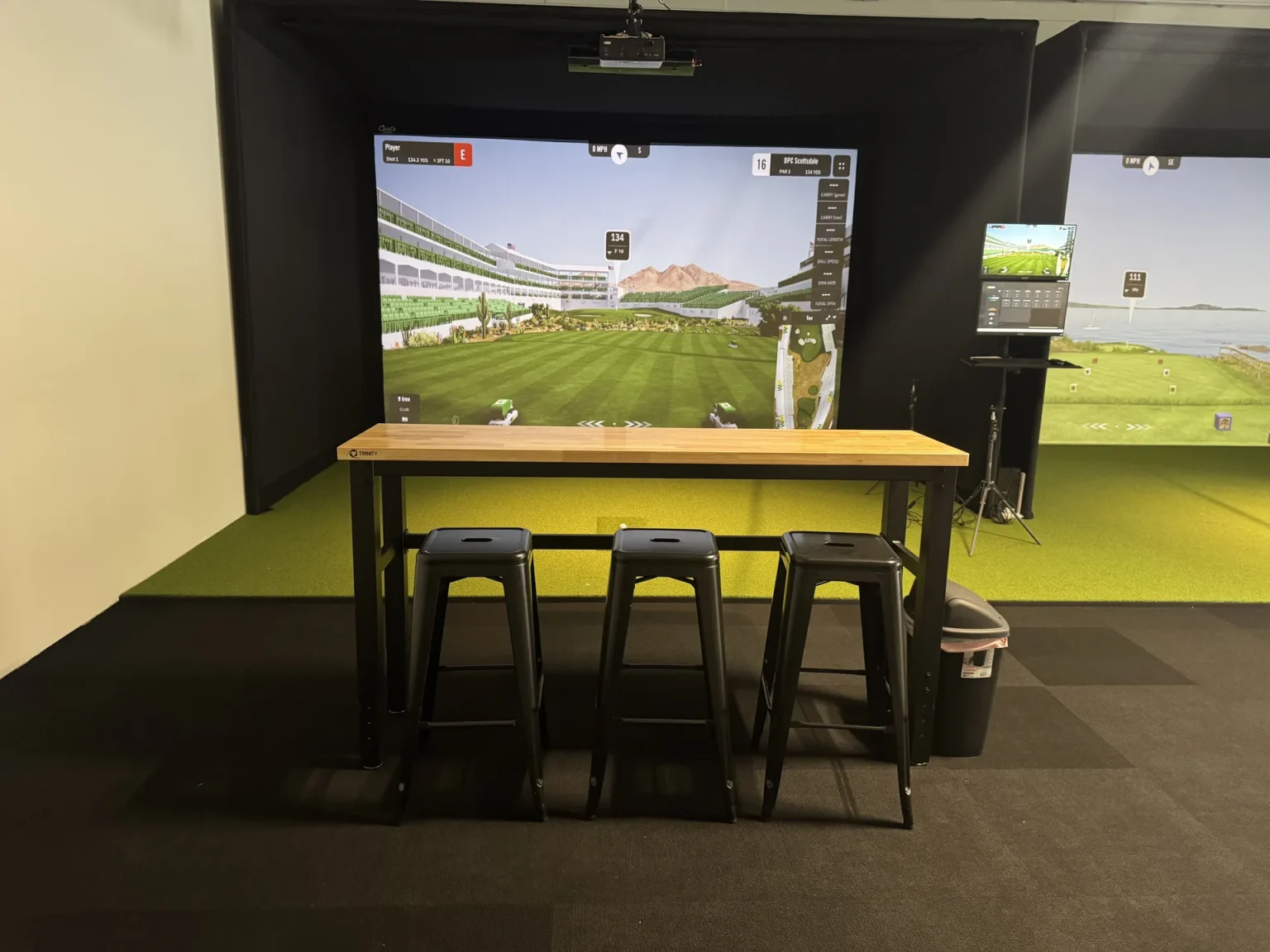GSPro simulator bay with high-top seating at Summit Golf Lab